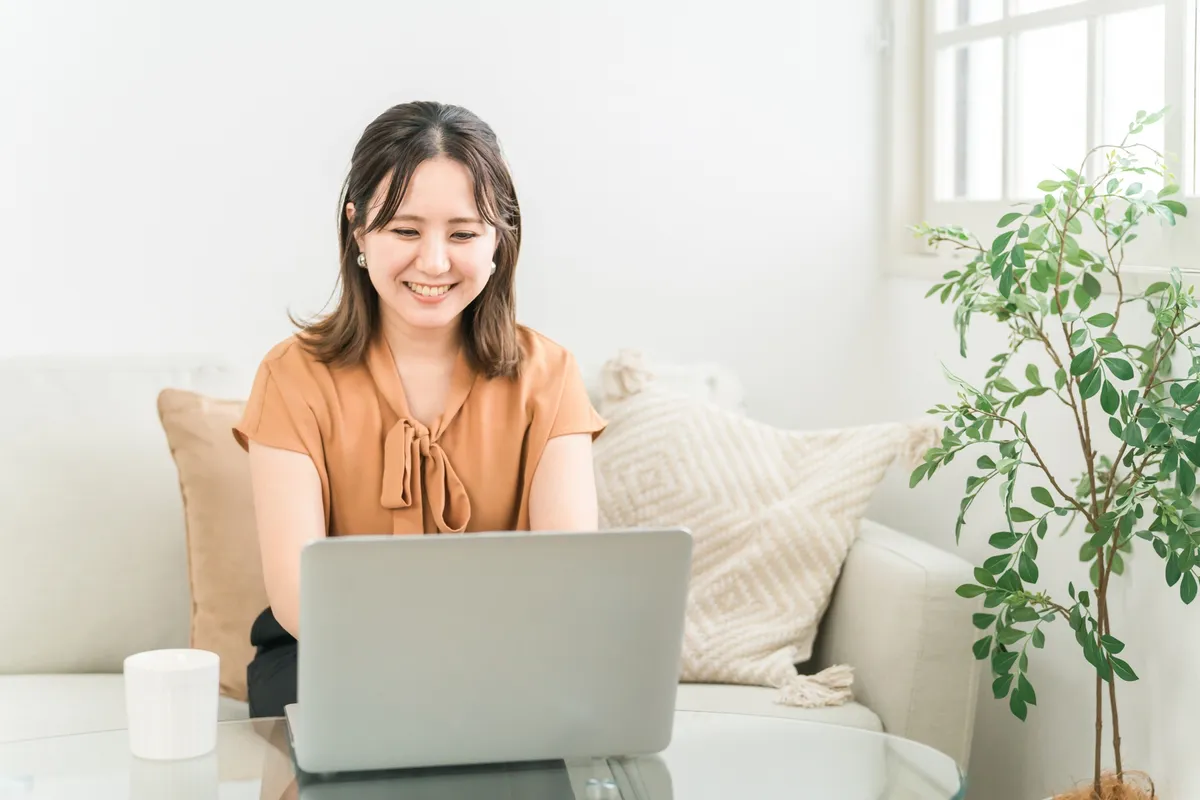 ソファでノートPCに向かう女性