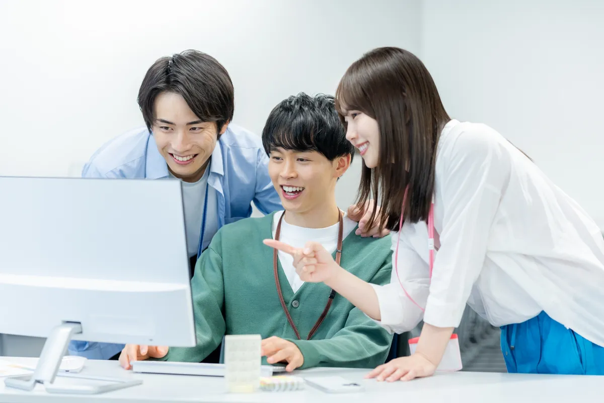 PCを囲む若手ビジネスチーム