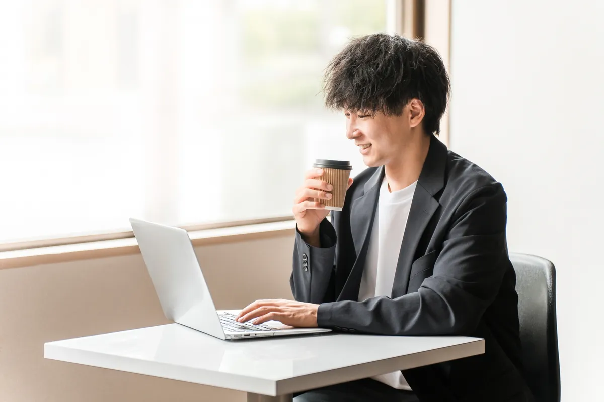 コーヒーを片手にPC作業する男性