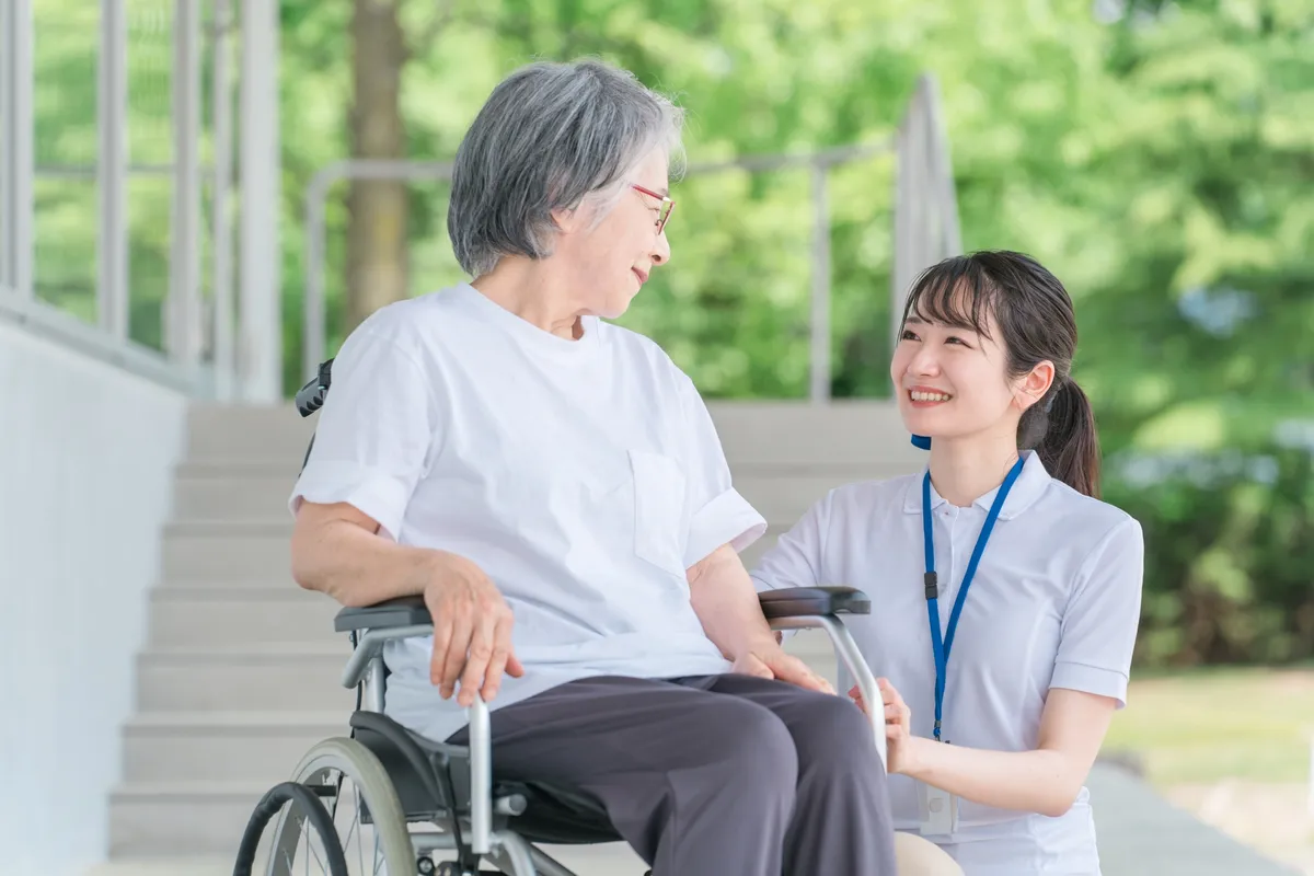 車椅子のシニア女性と介護士