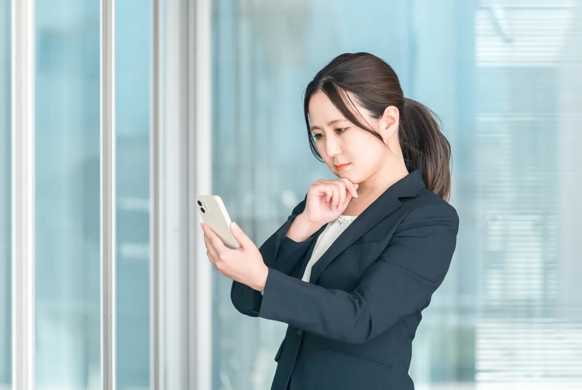 スマホを見て考えるビジネス女性